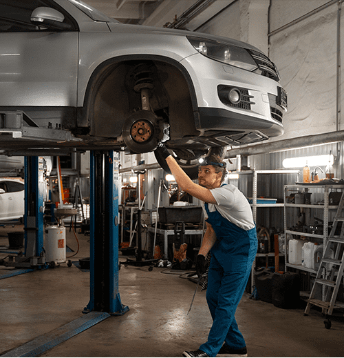 Mechanic inspecting a car on a hydraulic lift in an auto repair shop