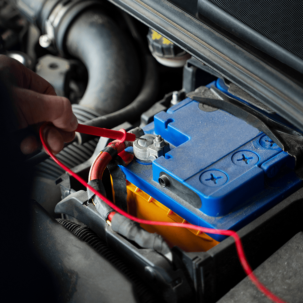 Mechanic testing car battery with red and black cables